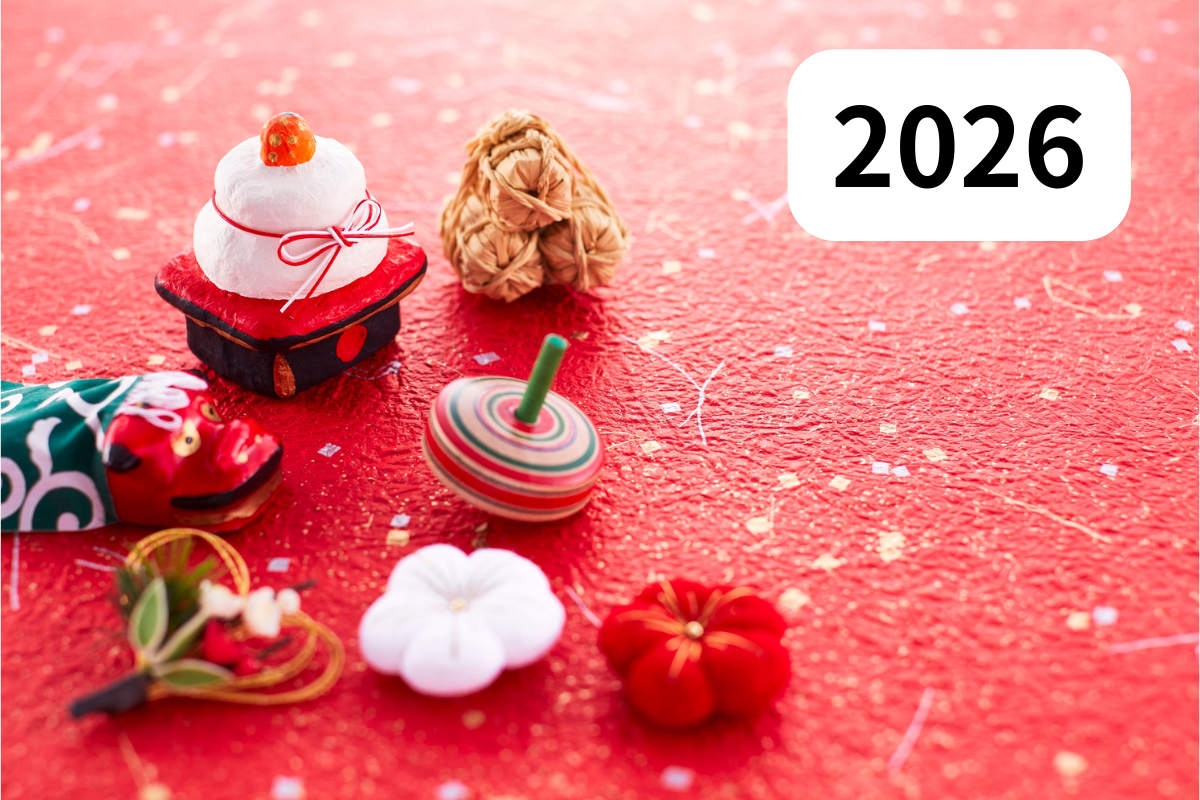 正月のイメージ写真:赤い背景に、2026の文字と米俵、鏡餅、獅子舞、こま、しめ飾り、梅の花が並ぶ。